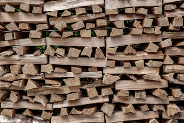 Firewood for the heating of the stove and fireplace, chopped into small pieces, are stacked perpendicular to each other.