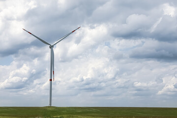 Modern wind turbine in field on cloudy day. Alternative energy source