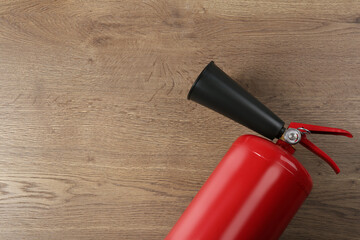 Fire extinguisher on wooden background, top view. Space for text