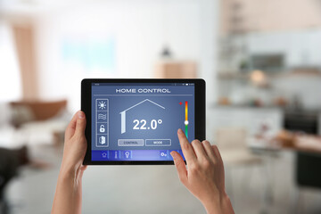Woman using tablet to set indoor temperature, closeup. Smart home automation system