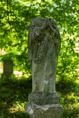 Old stone cemetary statue without head. Green plants in blurred background. Brusno type of cemetery...