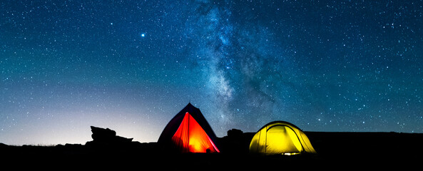 Tents glowing under the milky way at night. Camping in the mountains under the starry magical sky....