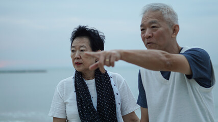 Obraz premium Asian senior elder couple holding hands looking sunset sea ocean together happy retirement life