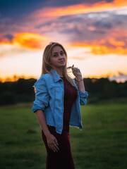 Attractive young woman in a bard dress and denim jacket portrait at sunset