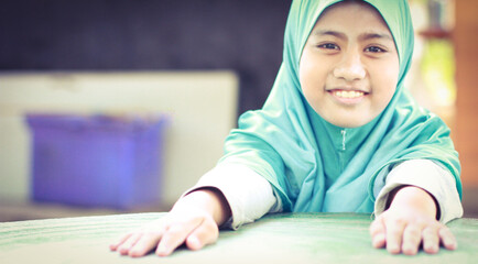 Naklejka premium Portrait of real-life Asian girl Muslim wearing green hijab smiling and sitting on a chair close up view image,