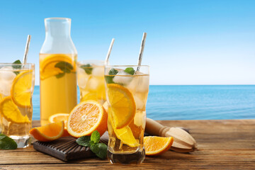 Tasty refreshing drink on wooden table against sea