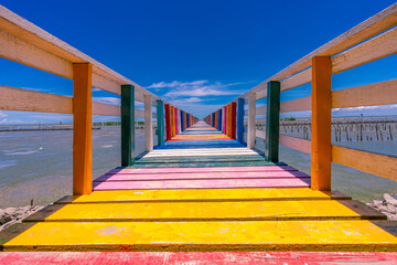 Rainbow bridge in Thailand.View of The colorful wood bridge extends into the sea under blue sky at samut sakhon province,Thailand.