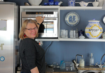 Fototapeta na wymiar mature woman in kitchen with microwave
