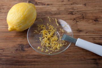 Lemon and a knife to remove the zest on wooden table