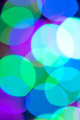 Christmas or New Year defocused festive bokeh background in trendy purple-blue-green color closeup. Vertical orientation.