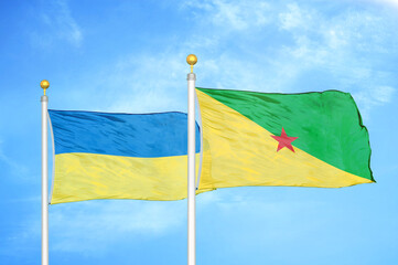 Ukraine and French Guiana two flags on flagpoles and blue sky