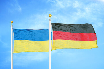 Ukraine and Germany two flags on flagpoles and blue sky