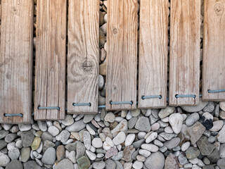Wooden boards on pebbles. A road on a pebble beach. Planks on sea stones