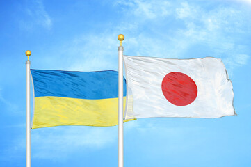 Ukraine and Japan two flags on flagpoles and blue sky