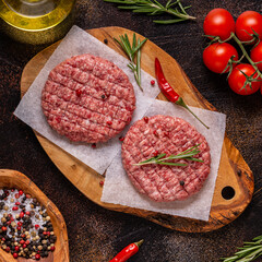 Fresh raw minced homemade grill beef burgers on wooden chopping board