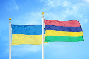 Ukraine and Mauritius two flags on flagpoles and blue sky