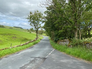 Country road, with dry stone walls, old trees, and a cloudy sky near, Lothersdale, Keighley, UK