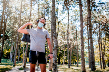 Young man in sportswear with a medical mask on his face going on training.