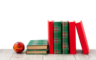 Naklejka premium Back to school, pile of books in colorful covers and red peach on wooden table with empty white background. Distance home education. Quarantine concept of stay home