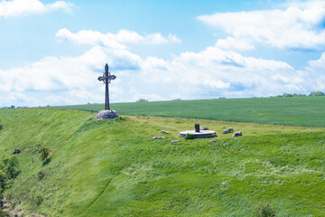Fototapeta premium Monument cross on a green field with a blue sky