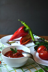 Tomatoes,peppers, spices and sauce in a white bowl on a dark background