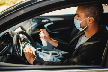 Man with protective face mask cleaning car interior to prevent virus spread 