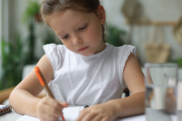 Little girl sit at desk, writing in notebook, do exercises at home, little child handwrite prepare homework.