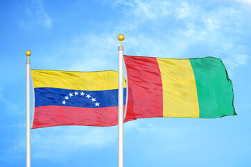 Venezuela and Guinea two flags on flagpoles and blue sky