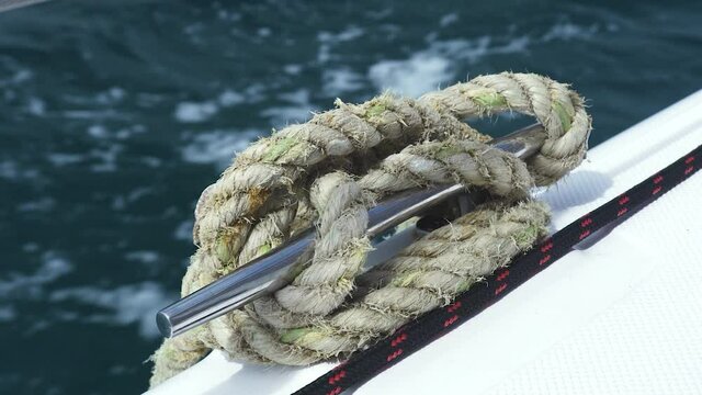 A view at the side of a traveling yacht in the ocean with rope tide to stainless bar. Fast moving boat in the ocean, view on the side edge.