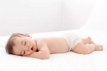 Full body shot of sleeping baby on white bed