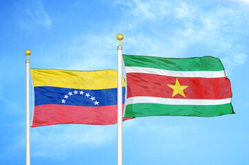 Fototapeta na wymiar Venezuela and Suriname two flags on flagpoles and blue sky
