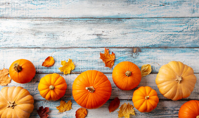 Pumpkins variety with autumn leaves. Blue wooden background. Copy space. Top view.