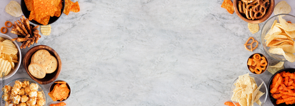 Poster assorted salty snacks. double side border with copy space. top view on a grey stone banner backgroun