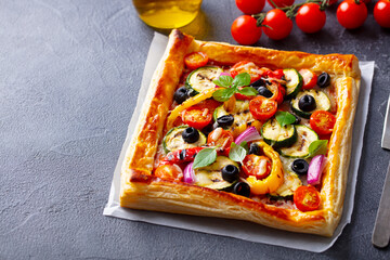 Puff pastry pizza with grilled vegetables. Grey background. Close up.