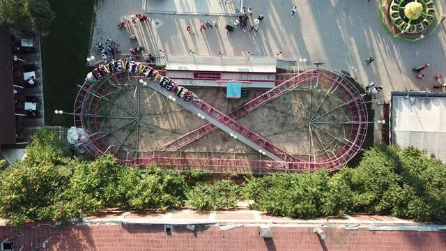 Aerial view of the medium size roller coaster at the amusement park in the city center. People are having fun at the holiday. 