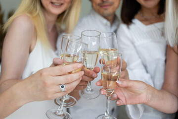 Close-up of friends hands holding glasses of champagne and making cheers. Corporate concept at work.