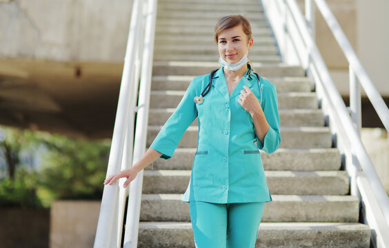 Female Doctor Or Nurse In A Protective Face Mask Walking Up The Stairs