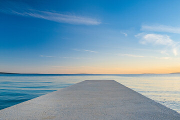 Croatia, island of Pag, beautiful seascape horizon on Adriatic Sea and long dock on sunny evening
