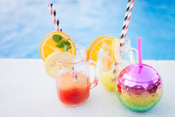 Glasses with tasty cocktails near swimming pool
