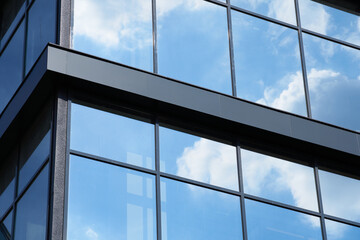 facade of a modern building on a bright Sunny day, blue sky and clouds reflecting in a glass, beautiful exterior of the new building