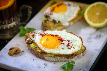 Fried egg sandwich with avocado and mushrooms.