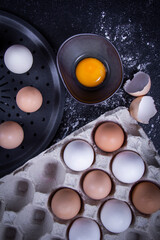 Egg yolk in a bowl with a hand mixer and a few healthy or broken eggs ready to bake a cake or food.