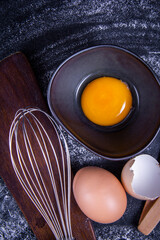 Picture of an egg yolk in a bowl next to healthy, broken native eggs.