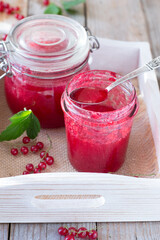 Red currant jam in glass jar on wooden table