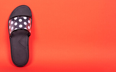 Rubber flip flop with dot pattern. Isolated on red background. Copy space.