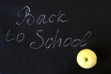 A ripe Apple on a black background with the inscription "Back to School", top view, close - up-the concept of the beginning of school classes