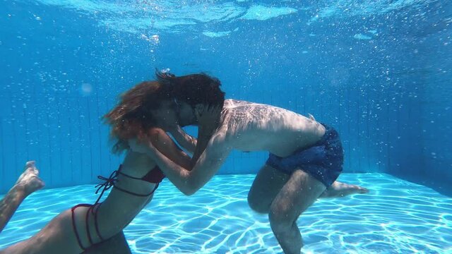 young couple kissing on the bottom of the swimming pool - underwater shot
