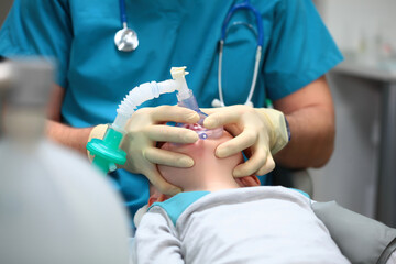 Preparing a young boy for dental surgery. General anesthesia. Treatment of multiple caries of baby...
