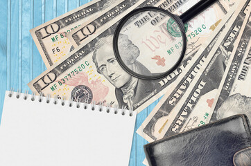 10 US dollars bills and magnifying glass with black purse and notepad. Concept of counterfeit...