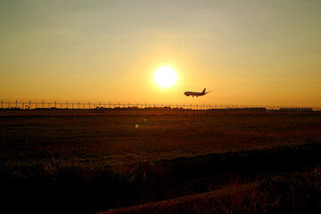 Silhouette of an airplane flying up against sunset sky